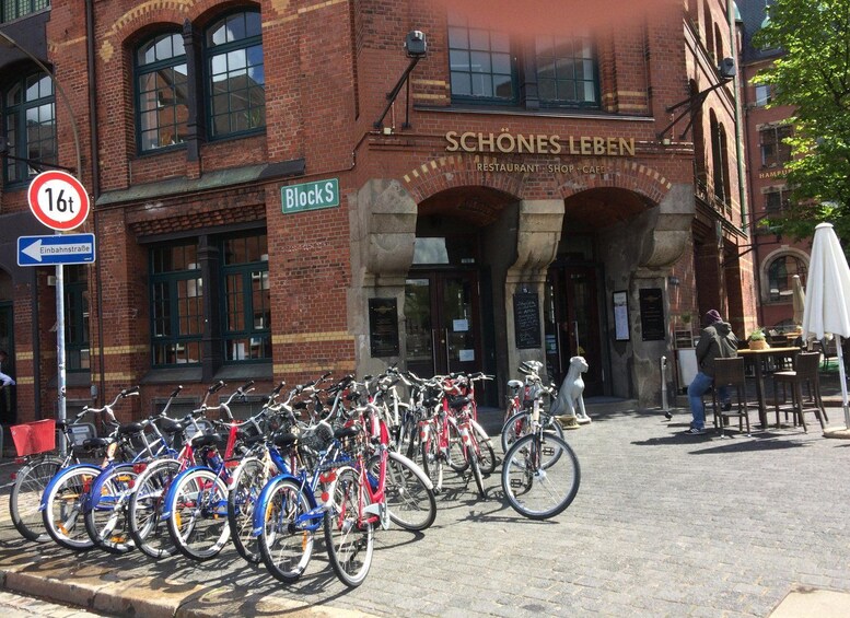 A brick building with a sign reading "SCHÖNES LEBEN" and a row of bicycles parked in front. 2