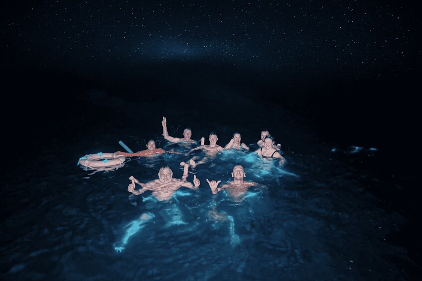 A group of people floating in a body of water under a starry night sky. 1