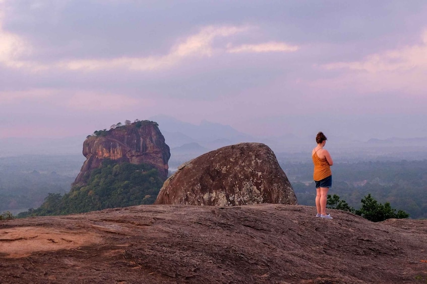 A person standing on a rock overlooking a mountainous landscape. 5