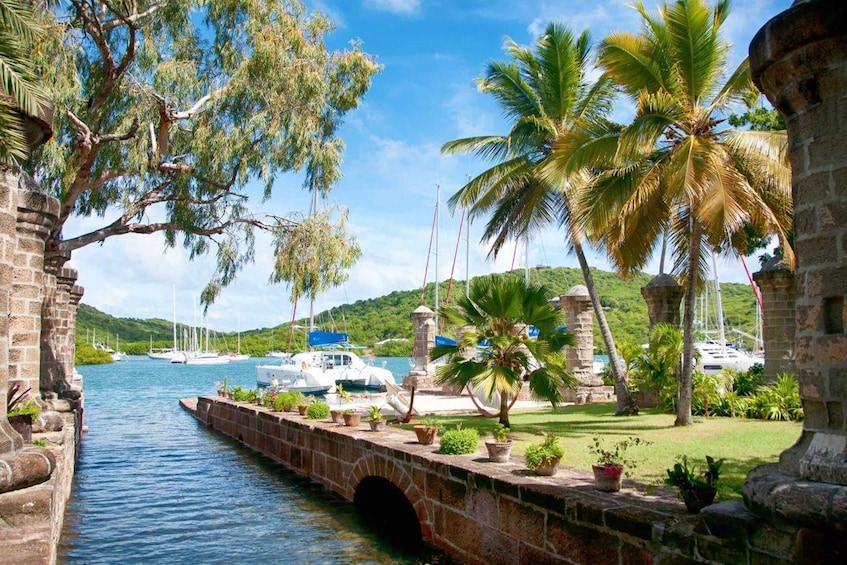 A stone bridge over water, palm trees, boats, and a mountainous landscape. 3
