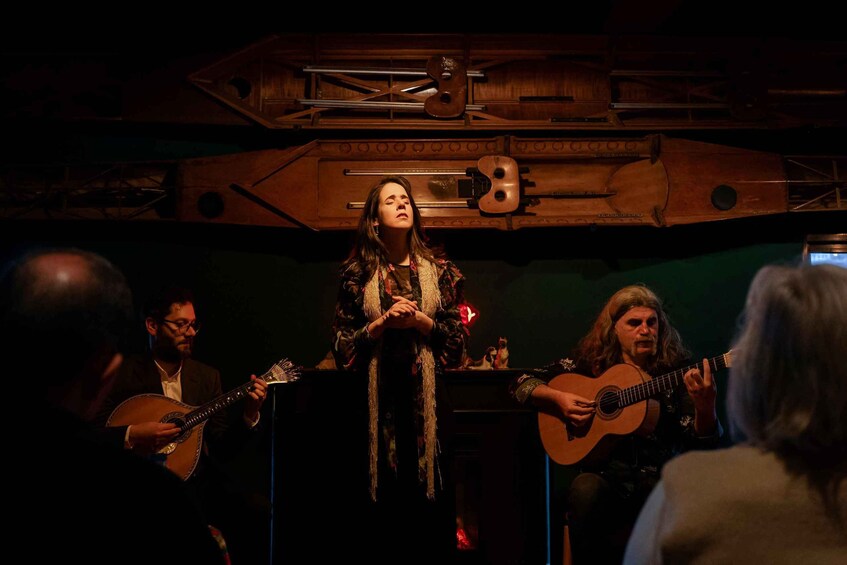 Una persona cantando en el escenario con dos guitarristas. 5