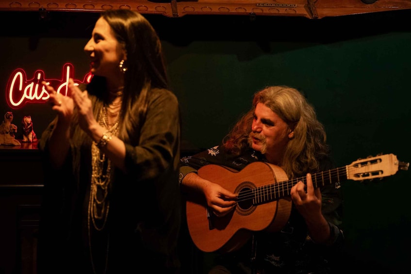 Dos personas actuando, una cantando y otra tocando una guitarra acústica. 2