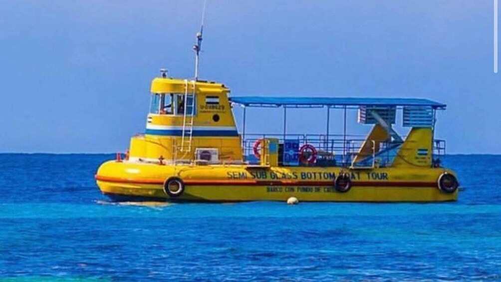 A yellow boat with the text "SEM SUB GLASS BOTTOM TOUR" on its side, floating on blue water. 1