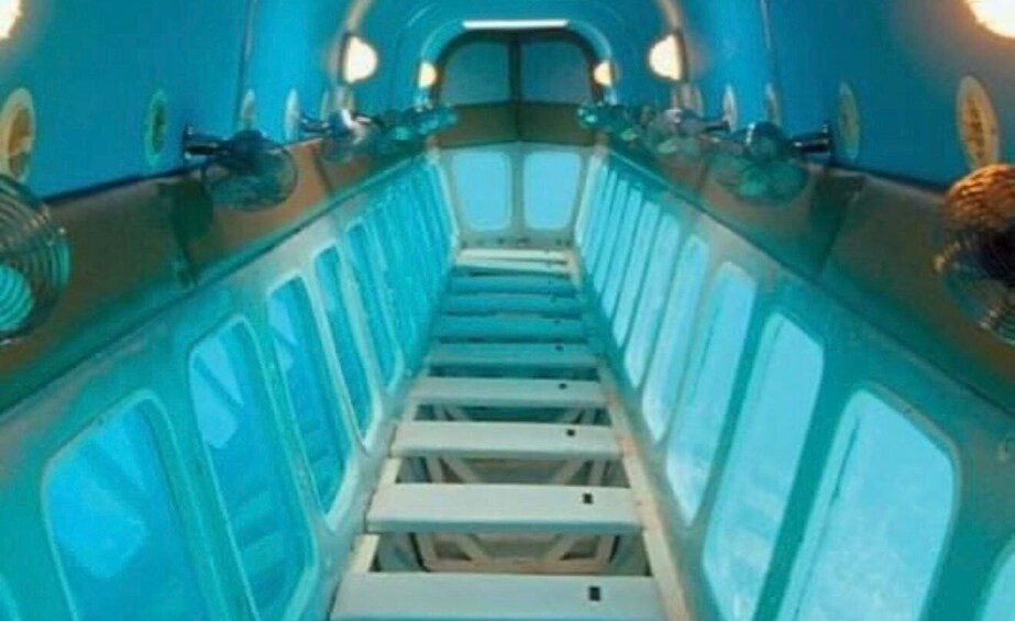 A narrow, enclosed space with blue walls and a central aisle. 3