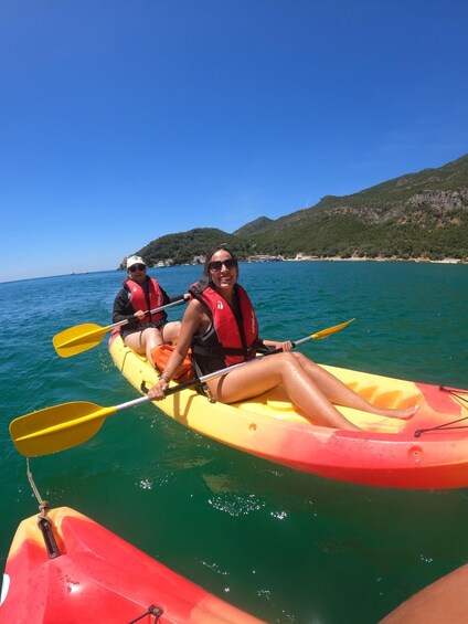 Two people kayaking on a clear day with mountains in the background. 3