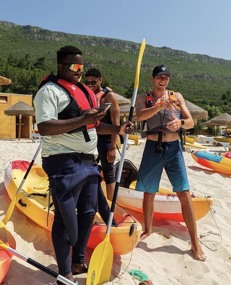 People on a beach with kayaks and a mountainous background. 2