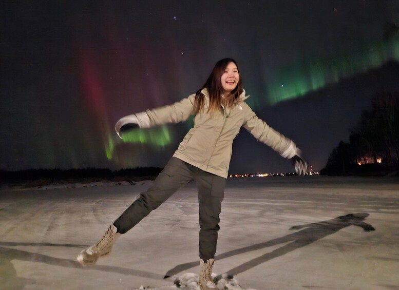 A person ice skating on a frozen surface with the aurora borealis in the background. 1