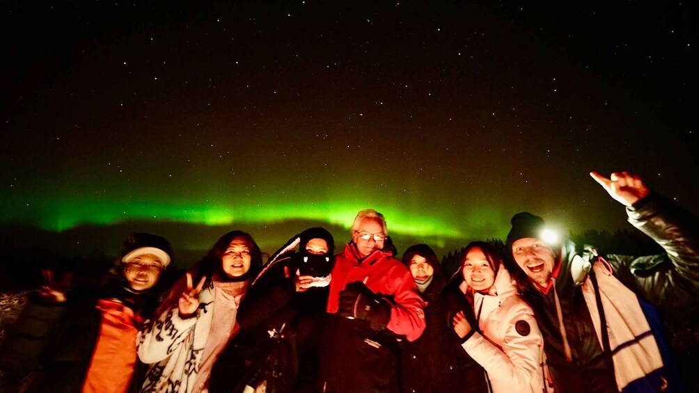 A group of people outdoors at night, with the aurora borealis in the sky. 2