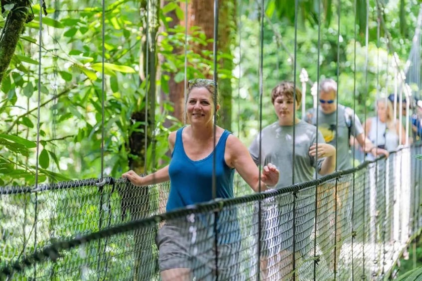 A group of people walking on a suspension bridge in a forested area. 3