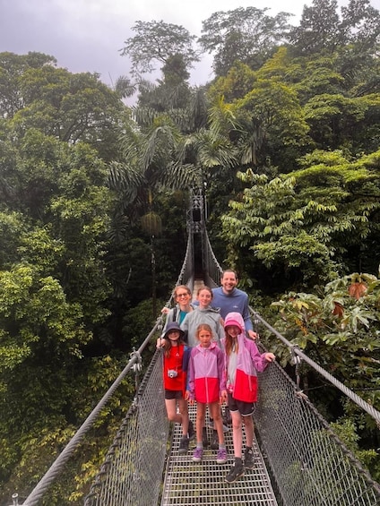 A group of people on a suspension bridge surrounded by dense tropical foliage. 1