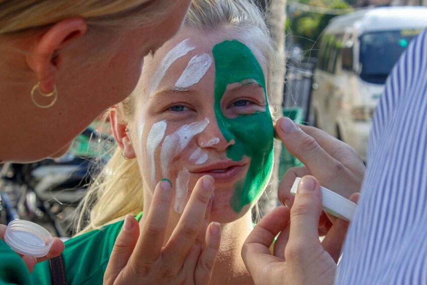 A person applying green and white face paint. 3