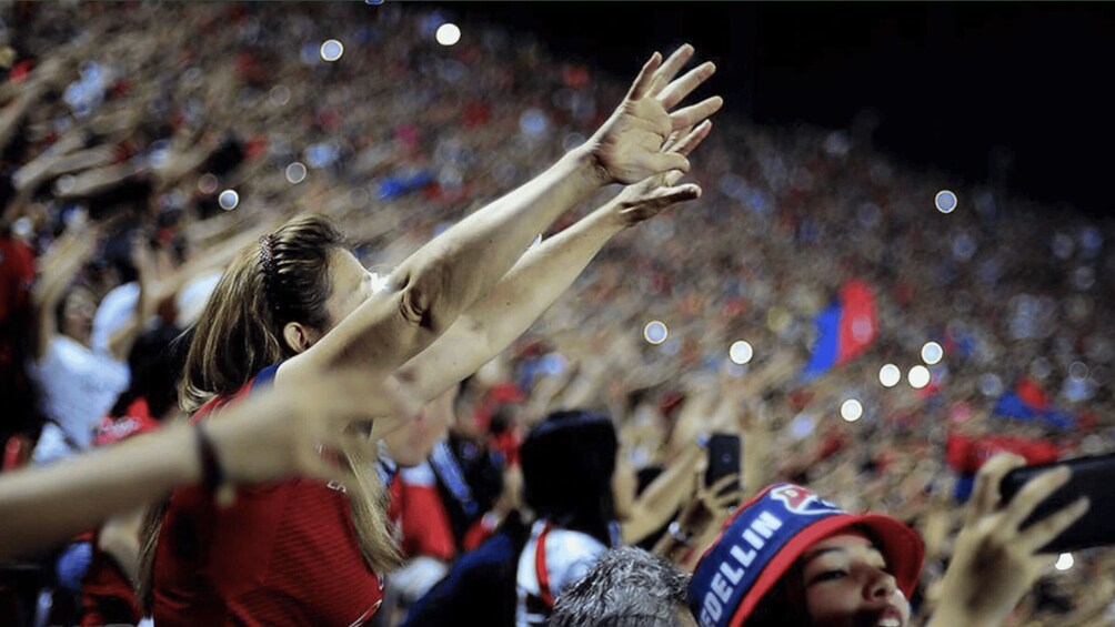 A crowded sports arena with people holding up their hands. 1