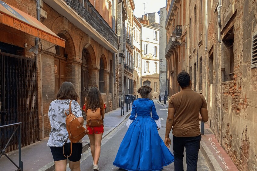 A narrow street lined with historic buildings, a restaurant sign, and a pedestrian walkway. 2