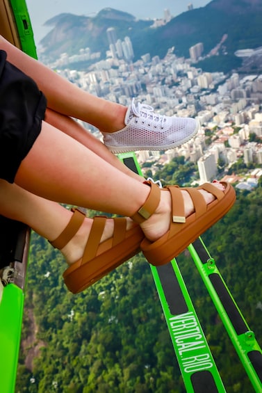 A person's legs in a brown sandal and white sneaker, with a cityscape in the background. 4