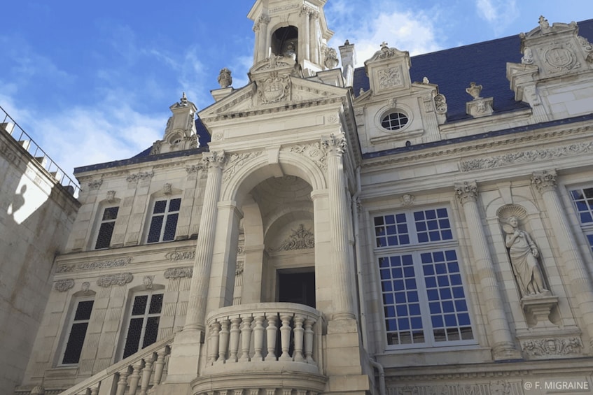 A classical building with ornate columns, a balustrade, and statues. 4