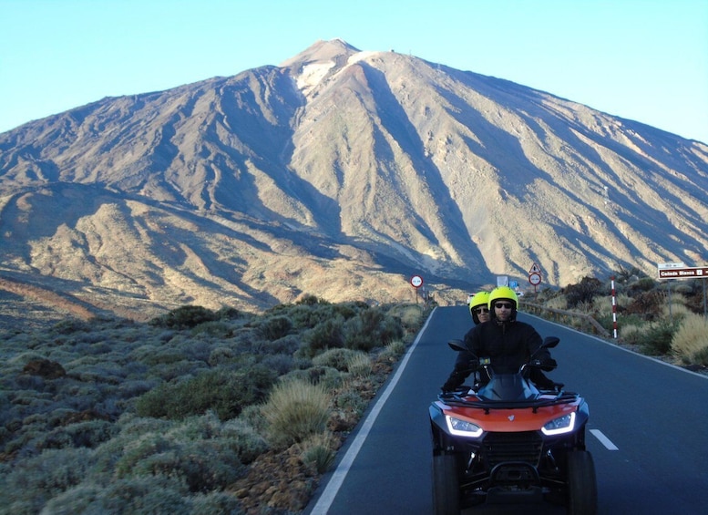 Una persona en una motocicleta sobre una carretera con una montaña al fondo. 1