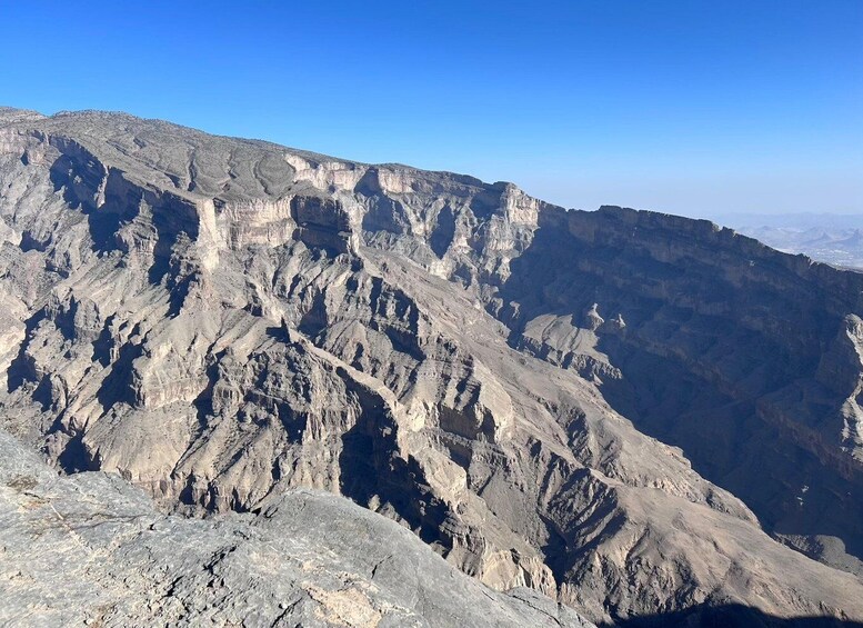 A rugged mountain landscape with steep cliffs and a clear blue sky. 1