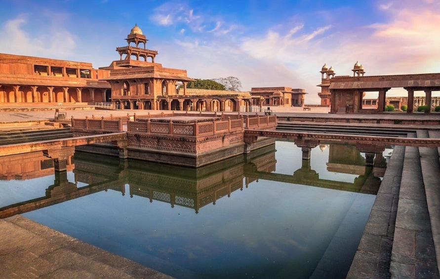 A historic water tank with intricate carvings, a reflection pool, and traditional architecture. 4