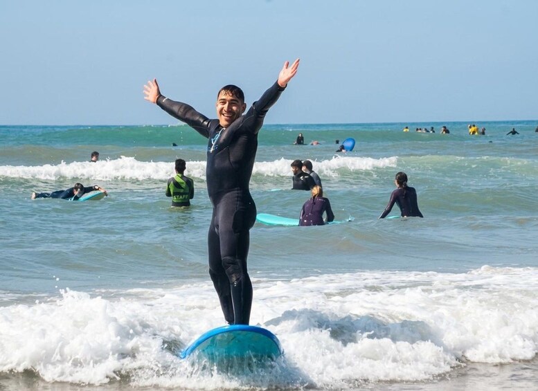 A person surfing on a wave at the beach with other surfers in the background. 2
