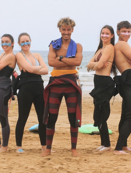 A group of people on a beach with surfboards and a green inflatable in the sand. 5