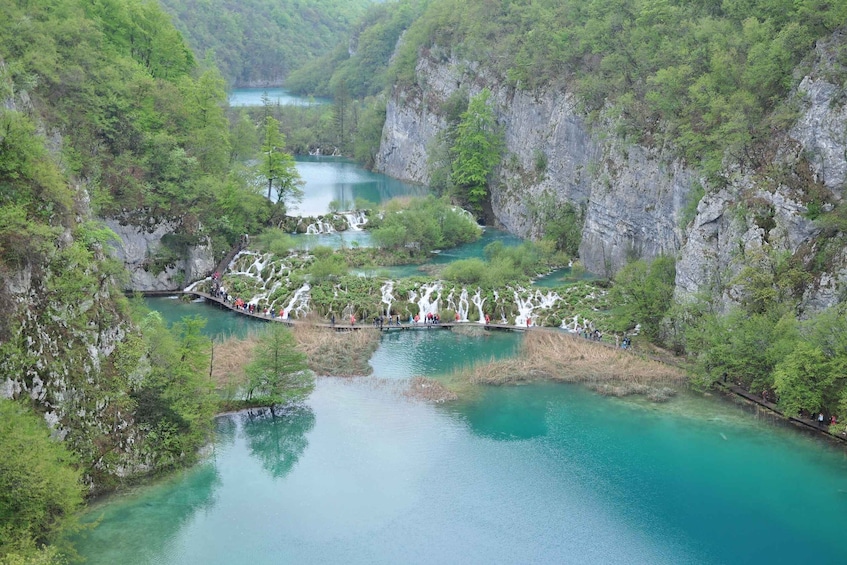 A river with clear turquoise water, surrounded by lush green trees and rocky cliffs. 4