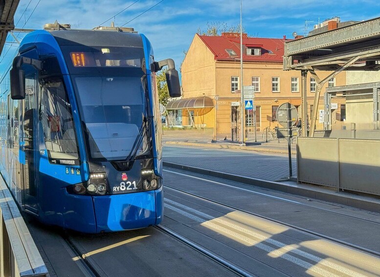 A blue tram with the number 821 on a tram track, passing by a building with a red roof and a sign that reads 'SAAL + HEALTHSHOP'. 5