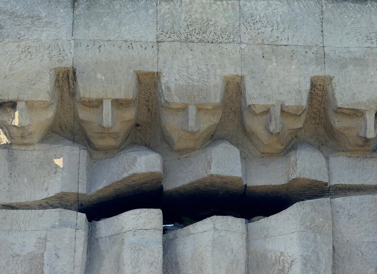 A stone wall with carved figures and a large crack. 4
