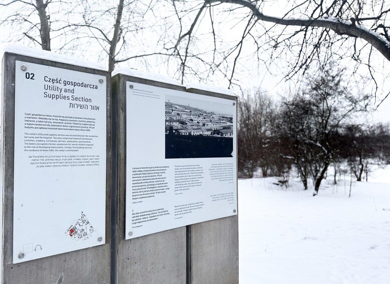 A historical signboard with text and a photograph, set against a snowy landscape with leafless trees. 2
