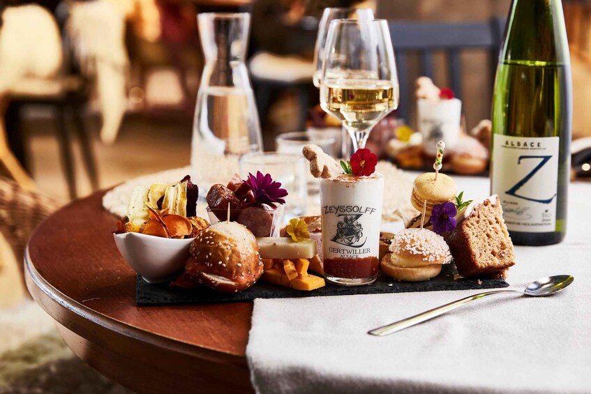 A table with various food items, a bottle of wine, and a glass of white wine. 1