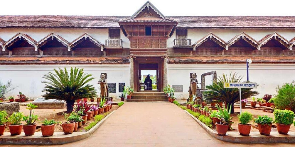 A traditional building with a tiled roof, a central entrance, and potted plants around it. 4