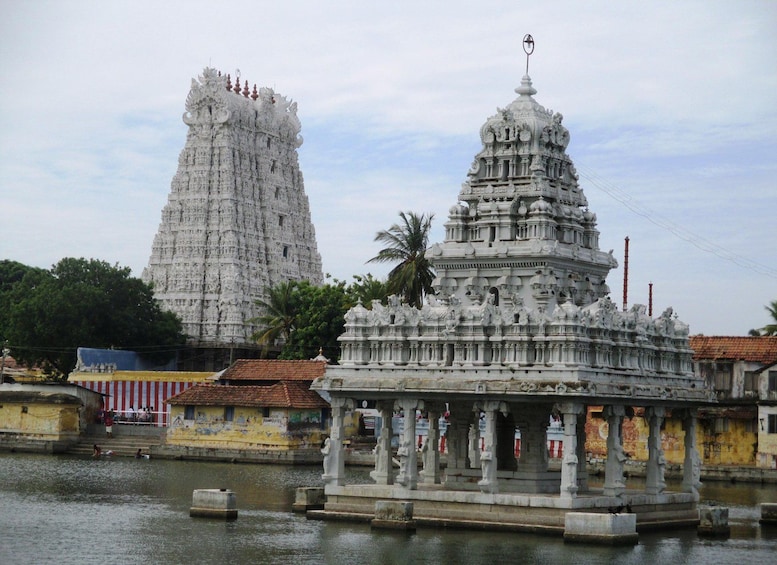 A temple with intricate carvings and a smaller shrine in front of it, with a body of water in the foreground. 5