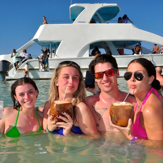Des personnes dans un bateau, tenant des boissons, avec de l’eau tout autour. 1