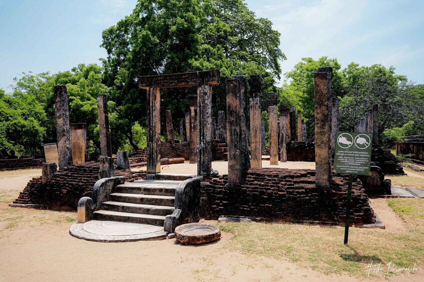 Ancient stone ruins with a central staircase and a signboard. 2