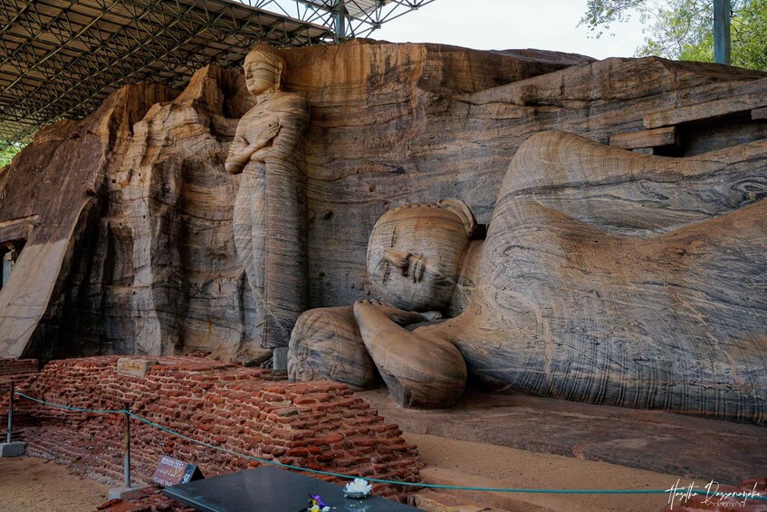 A large rock formation with a seated figure and a standing figure carved into the rock. 3