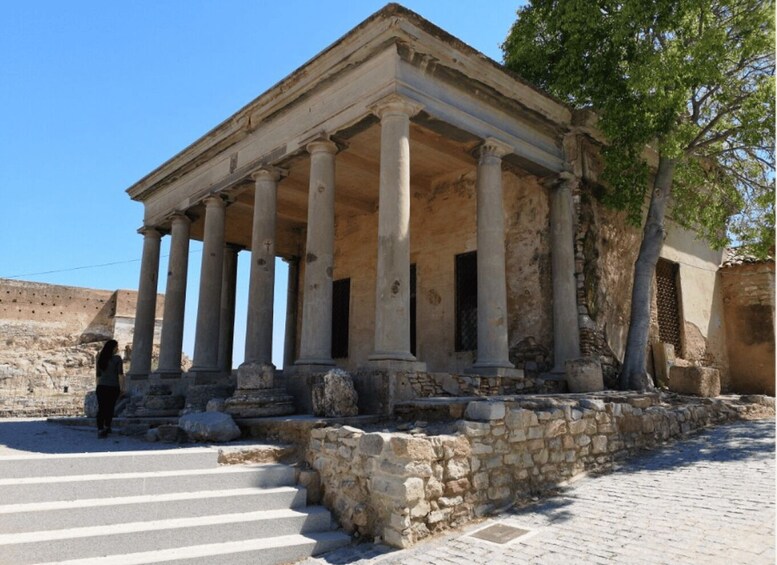 An ancient temple with columns and steps leading up to it. 3