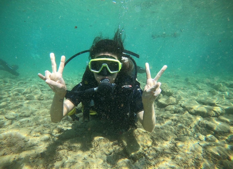 A diver underwater making a peace sign with their hands. 2