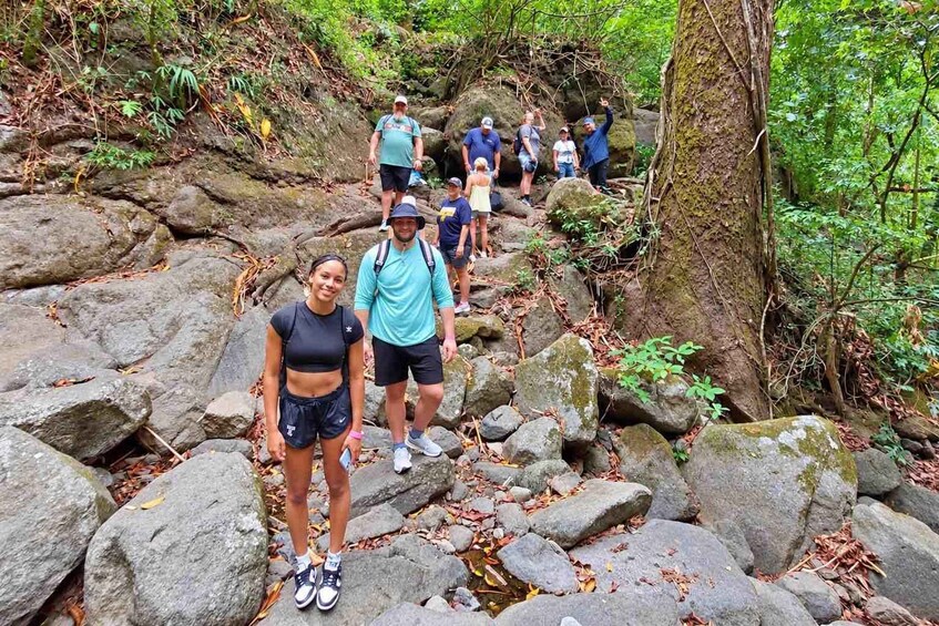 A group of people hiking on a rocky trail surrounded by dense forest. 4