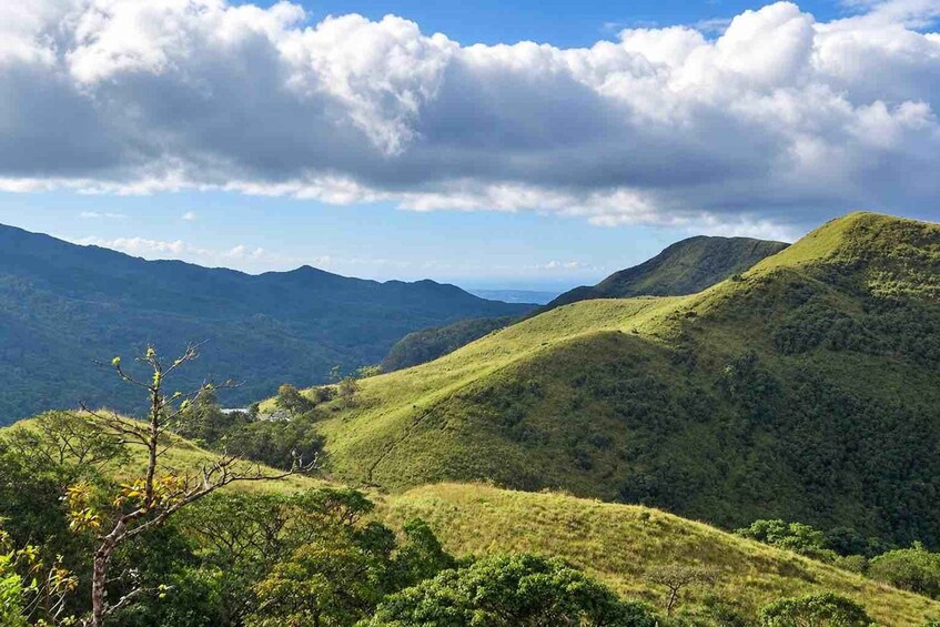 A mountainous landscape with lush green hills and a clear sky with clouds. 2