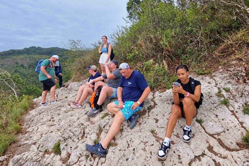A group of people sitting on a rocky hillside with a forested valley in the background. 3