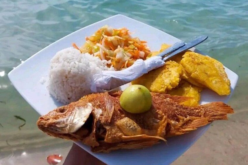 A plate of food with rice, fried plantains, and a whole fish. 3