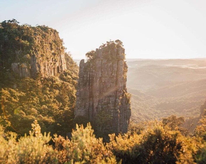 En stejl klippe med frodig vegetation i forgrunden og en vidtstrakt dal i baggrunden. 5