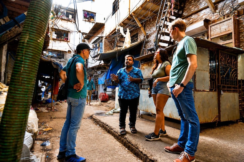 A group of people standing in a narrow alleyway with buildings on either side. 1