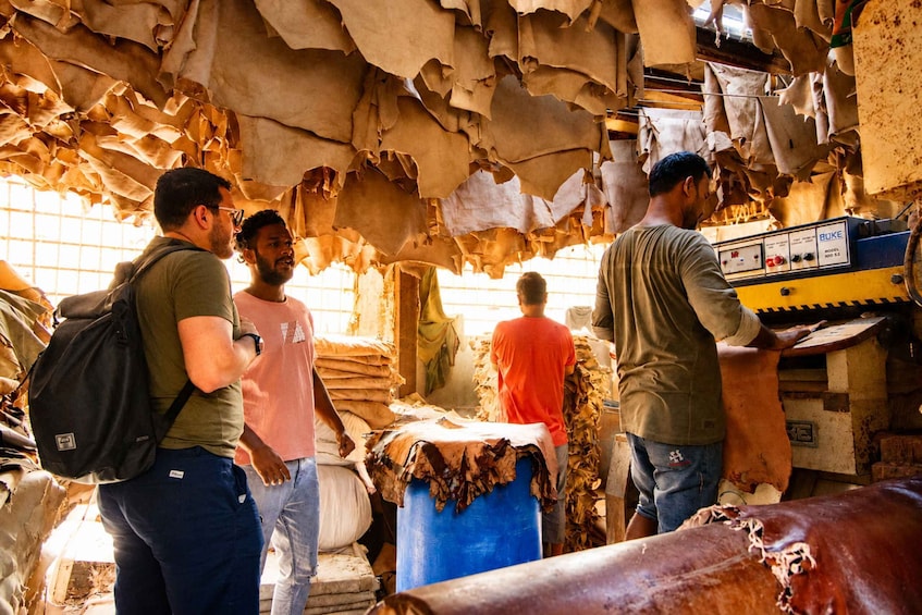 A group of people in a workshop with leather goods and a machine. 3