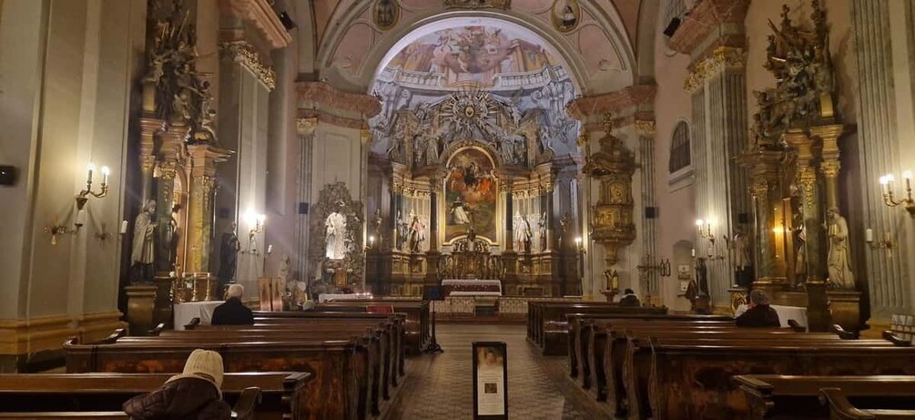 An ornate church interior with rows of pews, a central altar, and elaborate wall decorations. 1