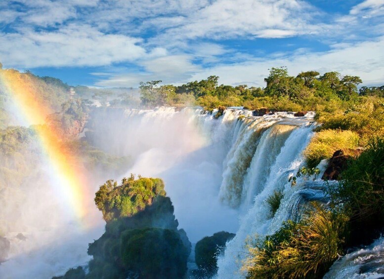 A waterfall with a rainbow, surrounded by lush greenery and trees. 4