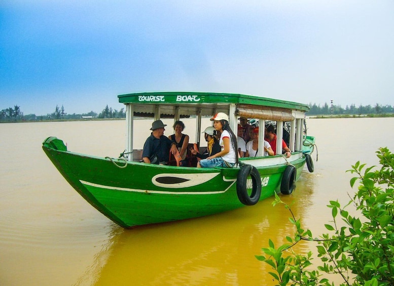 A green boat with the words "TOURIST BOAT" on the front, carrying passengers on a calm river. 2