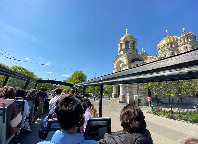 A bus with passengers looking at a large, ornate building with golden domes. 4