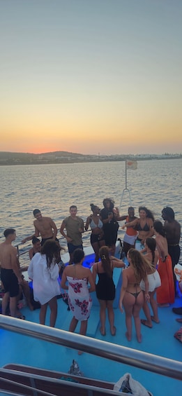 A group of people on a boat at sunset with a flag in the foreground. 5