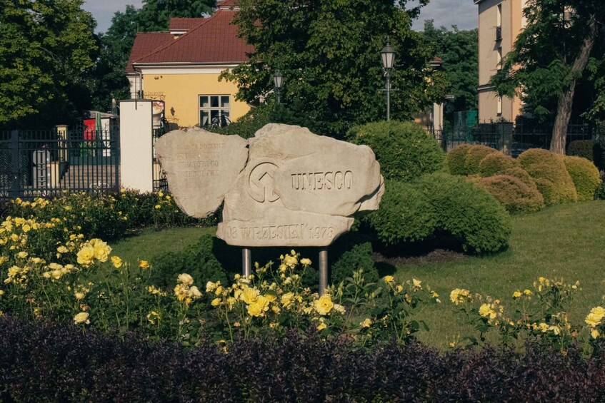 A stone monument with the inscription "UNESCO 08 WIZZESTEN 1978" surrounded by yellow flowers and greenery. 5