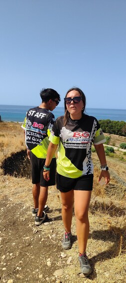 Two people walking on a dirt path with a coastal view in the background. 5